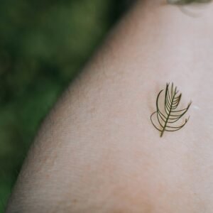 a woman's arm with a tattoo of a leaf on it